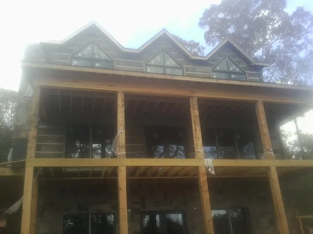Dormers and porch framing on a large log home under construction — Roof Coating work by our crew in Calera