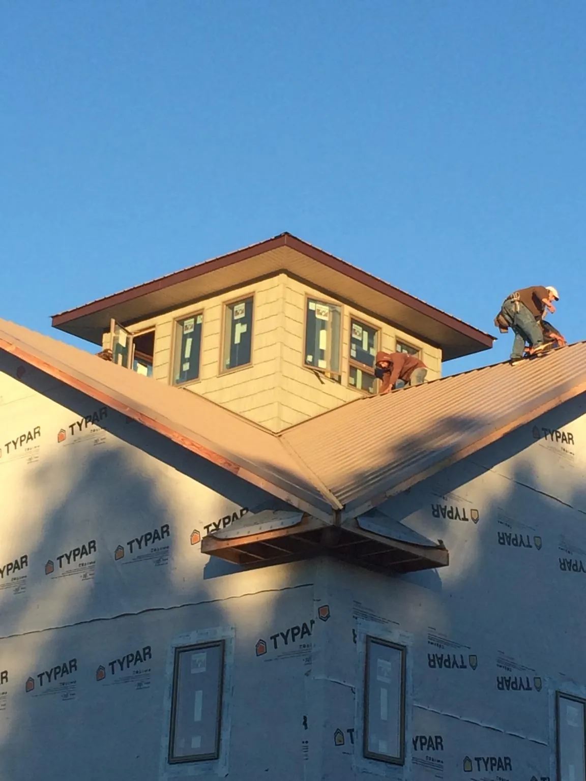 Roofers working around a rooftop cupola on a new metal roof at sunset — Roof Waterproofing in Calera by Roofing Brothers